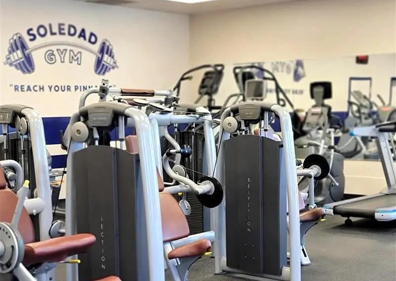 A gym interior featuring various machines and fitness equipment arranged throughout the room.
